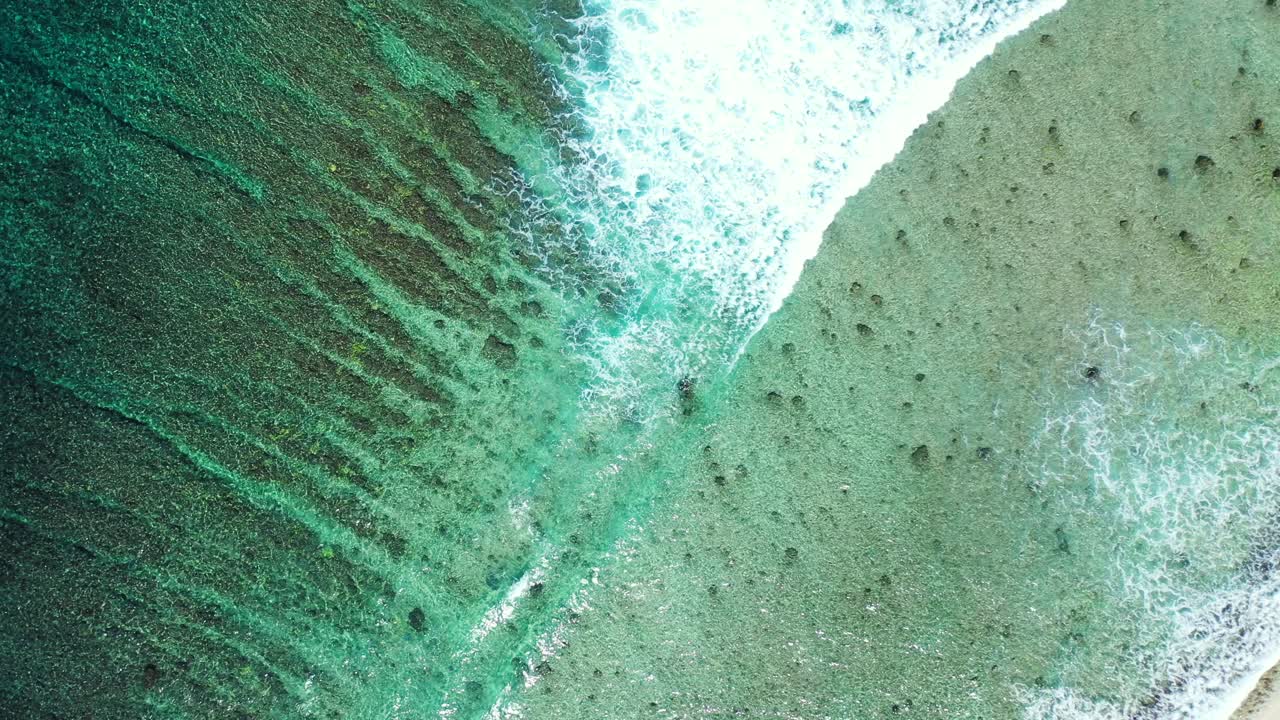 Peaceful sea texture with big white waves of ocean splashing on shore of tropical island with corals growing on shallow lagoon in Australia