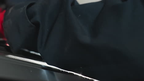 primer plano de una mano de trabajador con guantes rojos, agarrando una llave mientras trabaja en un componente mecánico, la reflexión de la luz en la mano agrega un efecto dramático
