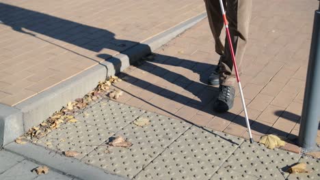 lone blind man detecting tactile tiles, walking to pedestrian crossing safe road