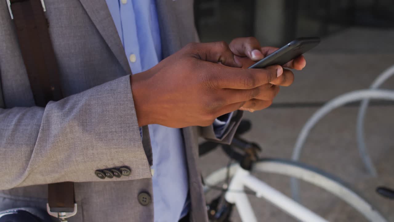 African american businessman using smartphone outside of modern office building