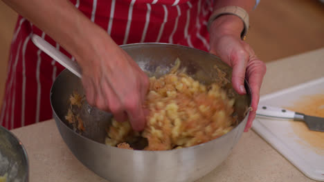 female hands mixing strapacky ingredients in a bowl, then add sauerkraut (fermented cabbage cut finely). close up