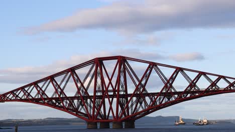 ship passing under iconic red bridge