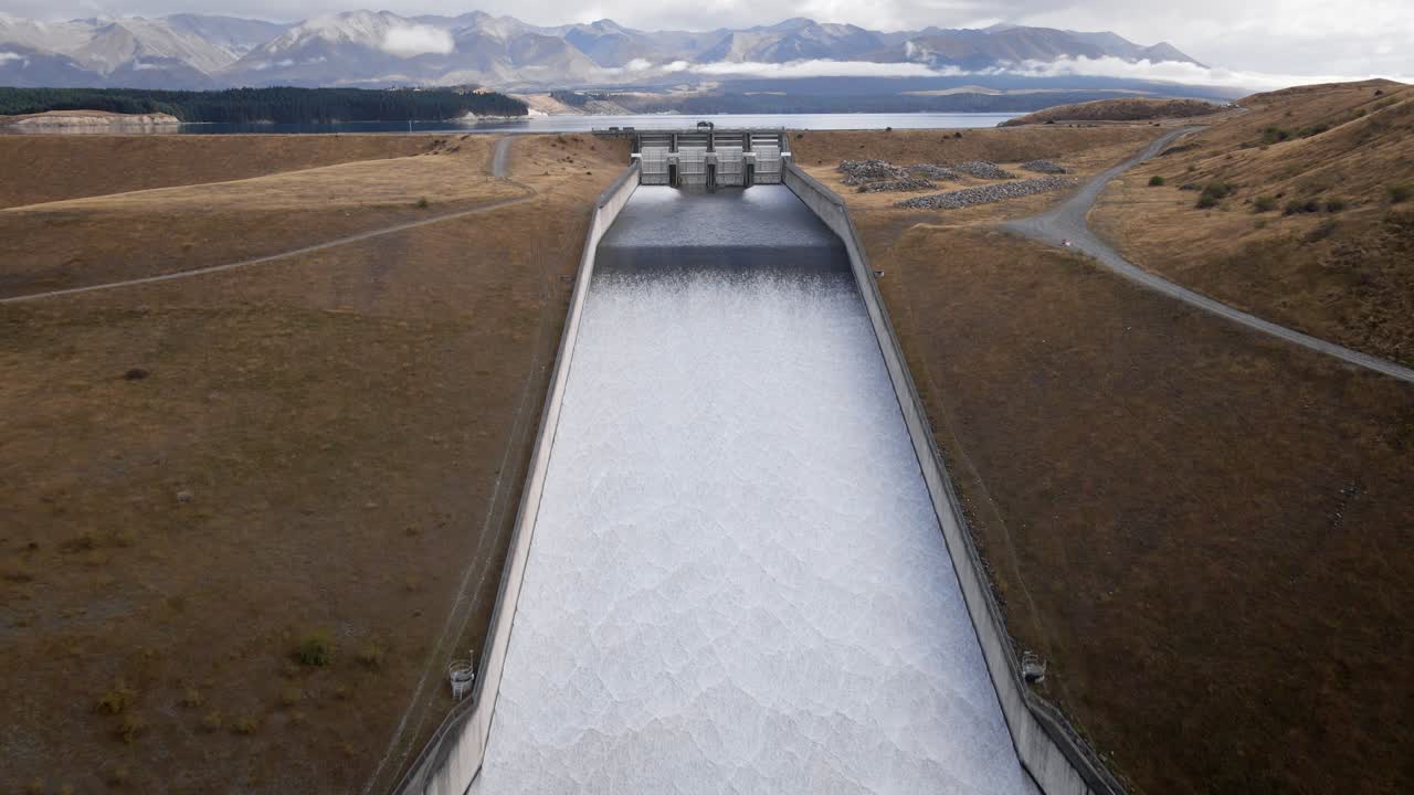 Large amounts of water exiting hydro dam and entering a beautiful blue river