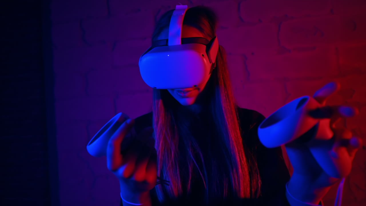 A young interested woman playing in VR games using VR glasses and controllers. Red and blue illumination. Slow motion