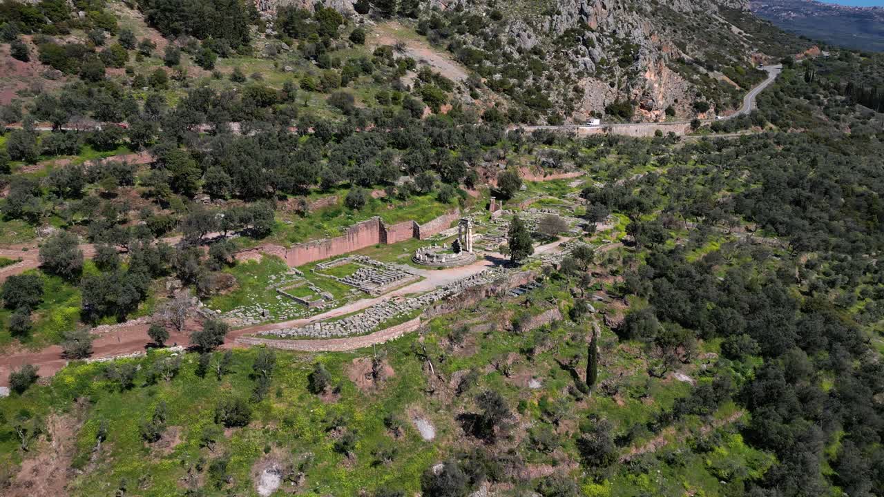 Aerial establishing of Athena Pronaia ruins with stone columns surrounded by greenery in Delphi, Greece