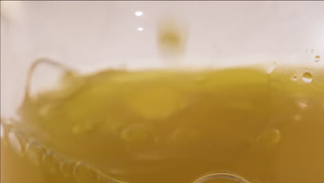 Close-up-shot-of-apple-juice-pouring-in-a-glass-bottle