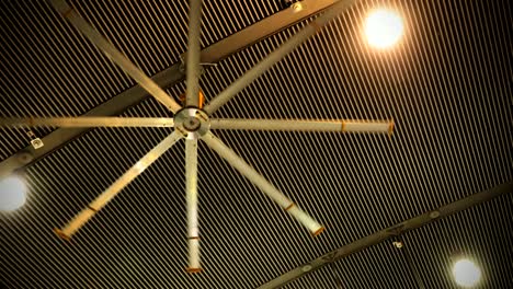 front view of huge fan spins around on industrial ceiling