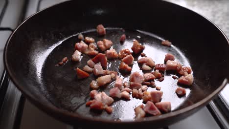 cocinar tocino en cubitos en la sartén en la cocina