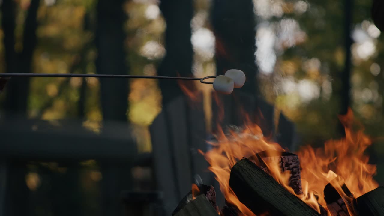 가을에 캠프 불 위에 두 개의 부풀어 오르는 마시멜로를 구워