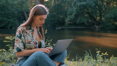 hermosa chica trabajando en una computadora portátil junto al lago