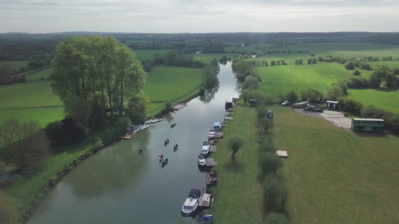Kayak and canoe outdoors water sports Adventure In River Thames With Calm Waters Surrounded By Lush Green Fields In Oxford, England - Drone Shot Tilting Down