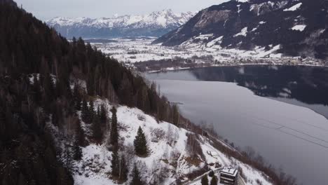 austrian alpine frozen winter lake in zell am see, aerial view, pull back