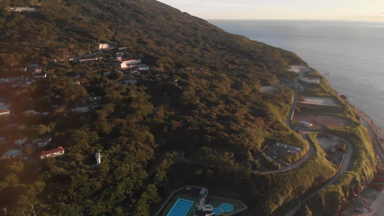 일몰 때 바다 옆에 울창한 초목이 있는 아름다운 섬 위로 움직이는 공중 기울기를 왼쪽