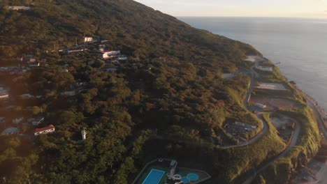 inclinación aérea izquierda hacia arriba sobre una hermosa isla con una densa vegetación junto al océano al atardecer