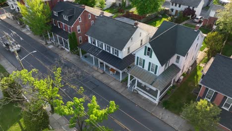 a slow cinematic aerial shot following an american road lined with colonial style houses in usa