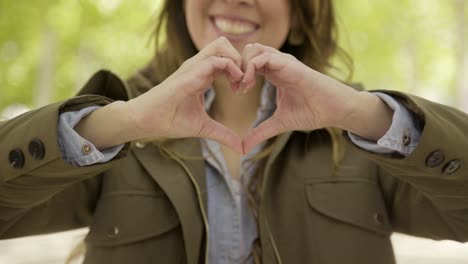 mujer sonriente haciendo forma de corazón con las manos.