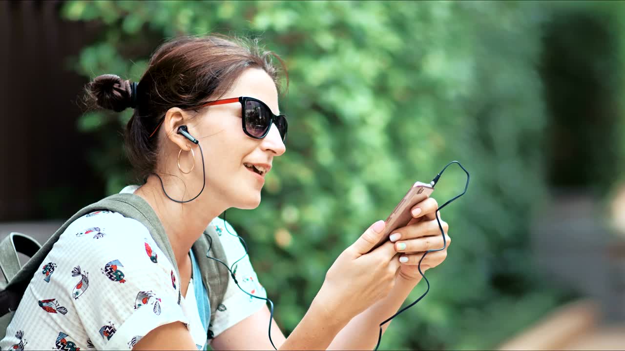 Giovane donna bellissima che ascolta musica, balla e canta nel parco