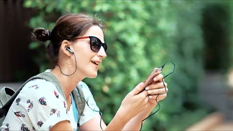 joven hermosa escuchando la música, bailando y cantando en el parque