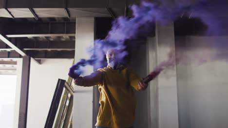 Mixed-race-woman-holding-blue-and-purple-flares-standing-in-an-empty-building