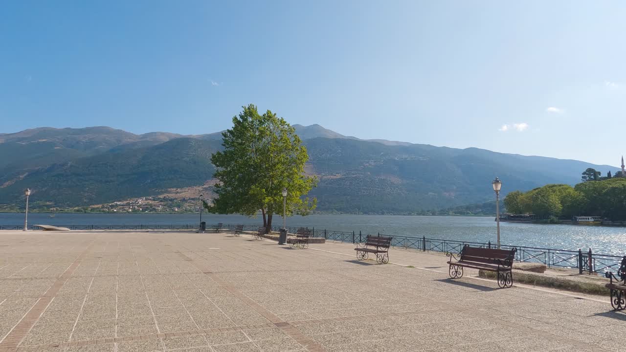 amplio paseo marítimo con bancos vacíos al lado del lago en ioannina, grecia