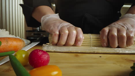 close-up of a chef's hands rolling sushi with a bamboo mat