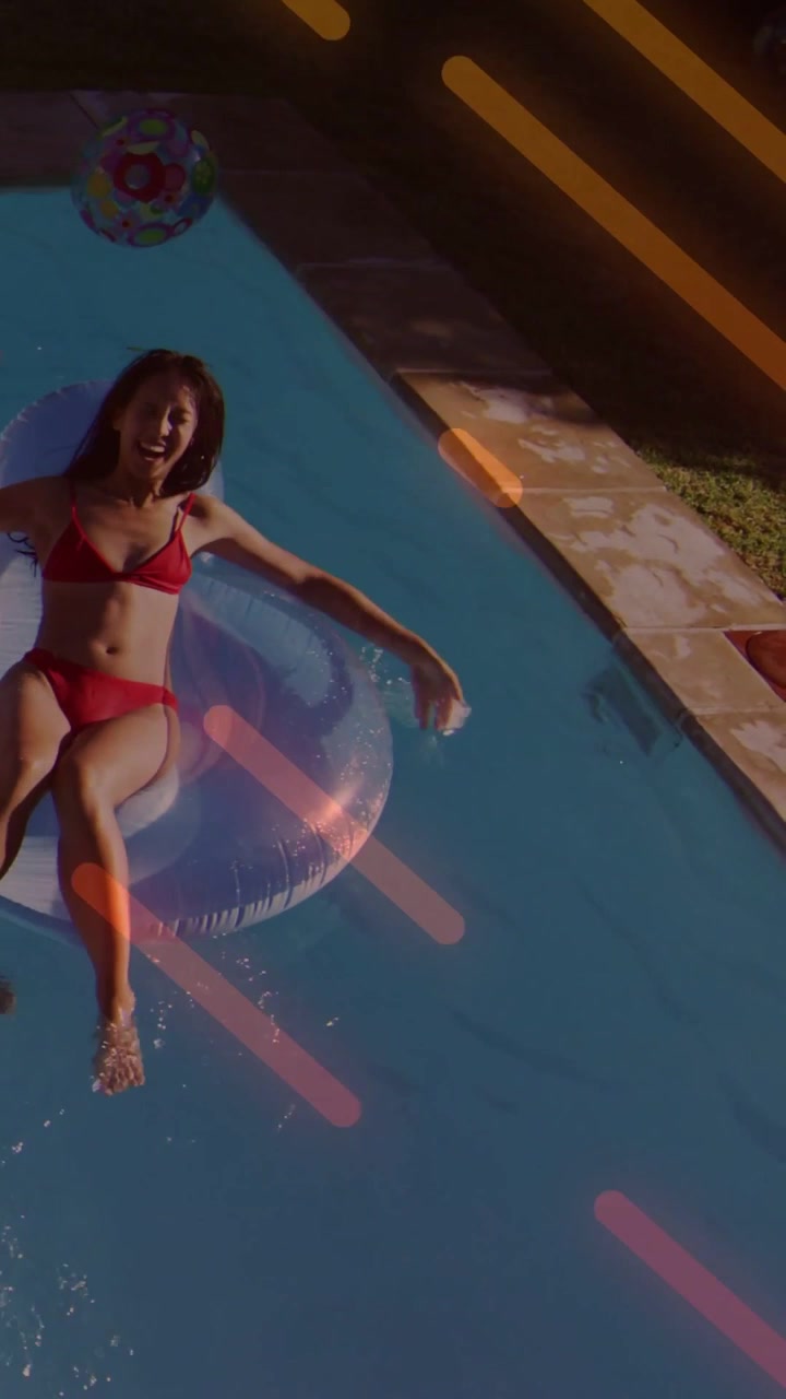 Woman on clear ring in pool, friend reaching, turning, kicking, light effects crossing ring for ads