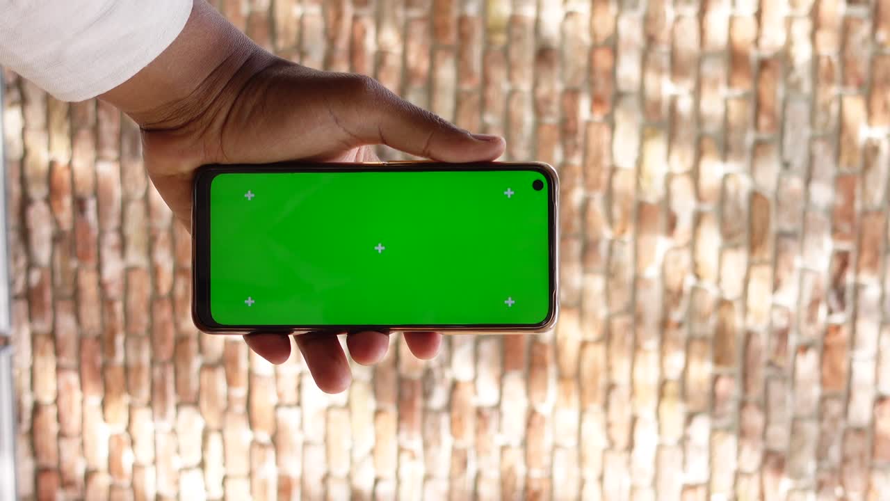 Smartphone with green screen held in hand