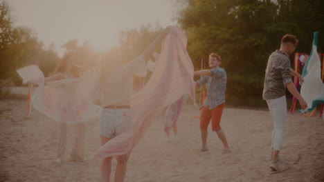 hombres y mujeres jóvenes balanceando sarongs en la playa
