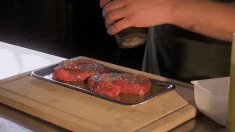 chef adds pepper on raw meat