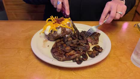 cutting into a ribeye steak with sautéed mushrooms on top