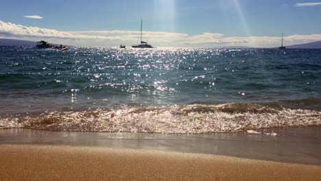 Beautiful-Maui,-Hawaii-sunset,-waves,-sand,-sailboats,-and-shimmering-sun-with-Lanai-in-distance,-HD