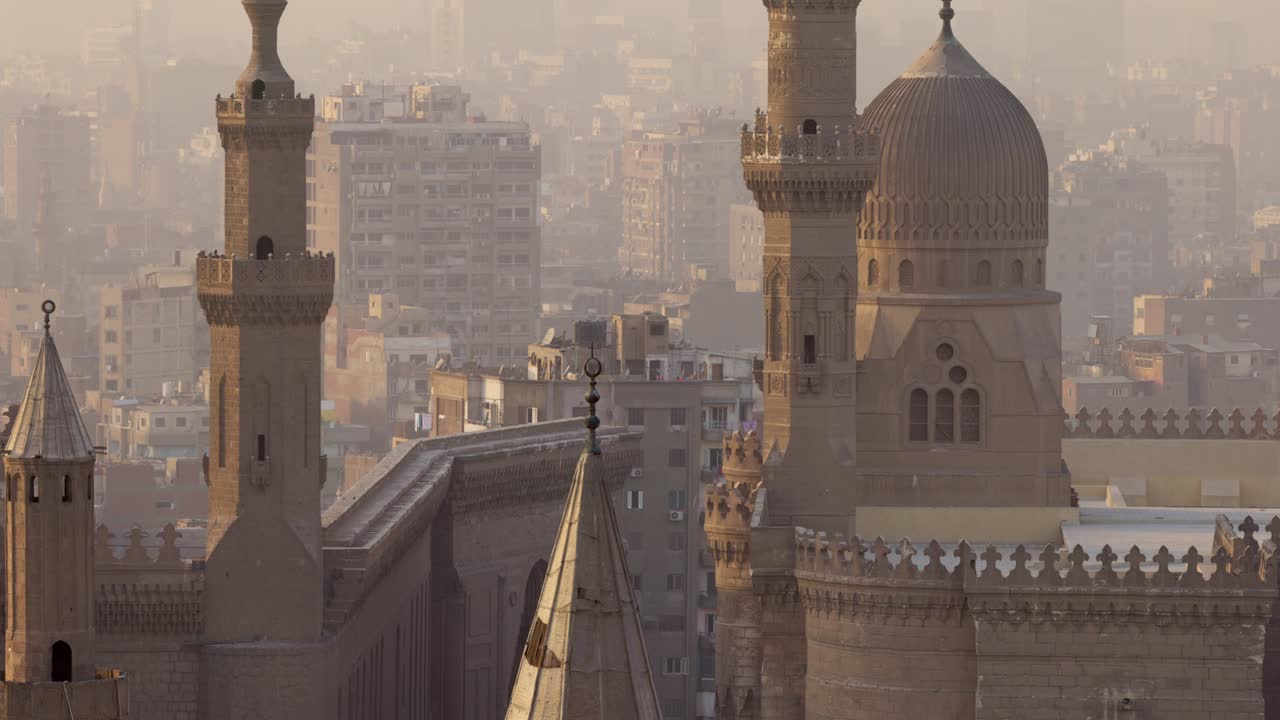 tilt up close shot de la mezquita del sultán hassan y la ciudad de el cairo, egipto. mezquita y casas en niebla ligera al atardecer