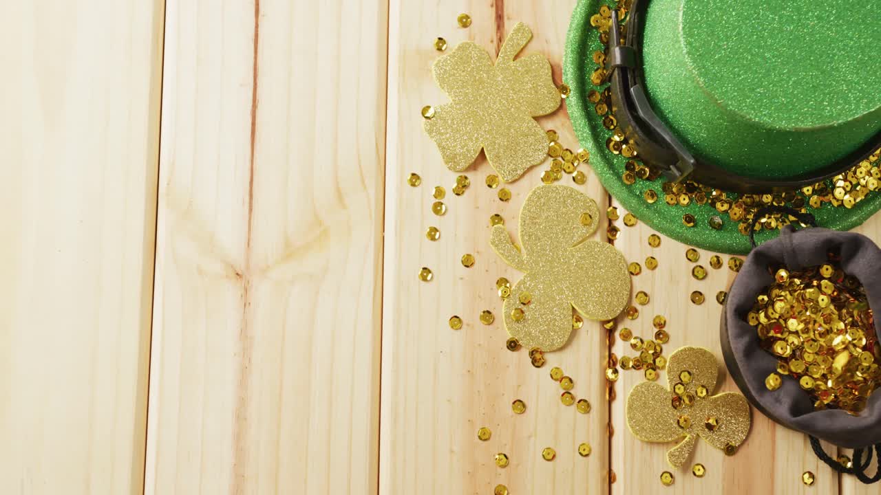 Video of st patrick's green hat, shamrock and bow tie on wooden background