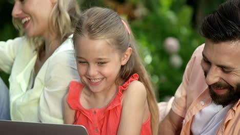 Portrait of cute family are sitting on the grass and using electronic devices