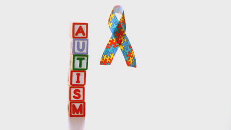 awareness ribbon dropping beside blocks spelling autism