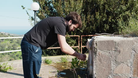 man washing hands at an outdoor fountain