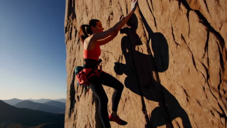 a woman rock climbing and rappelling on a rugged mountain face
