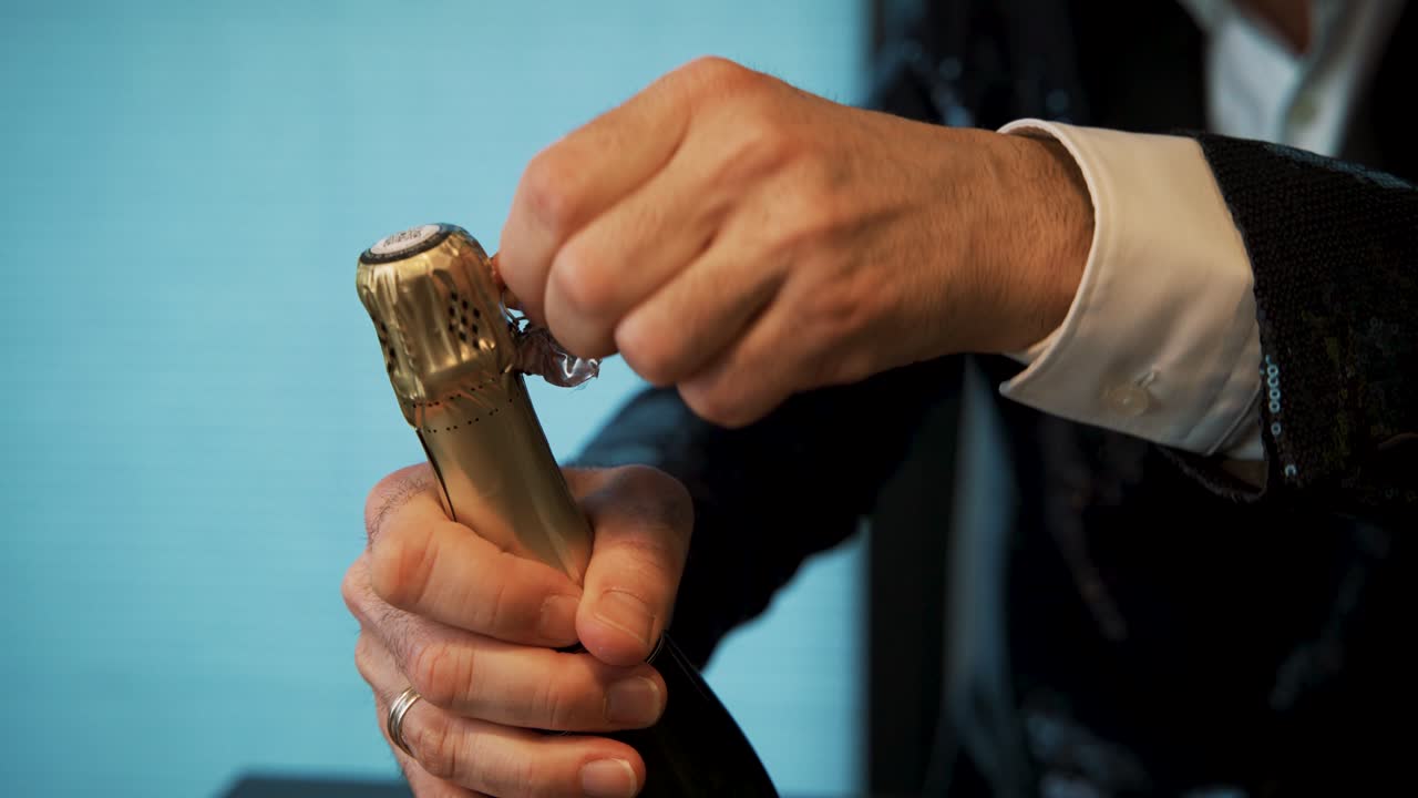 턱시도에 샴페인 병 은박지 포장, 뮤슬렛 및 코르크 개봉