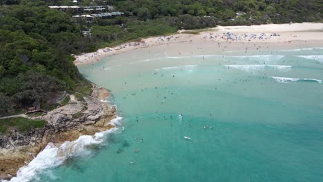 Touristen-Schwimmen-Und-Entspannen-Am-Strand-Mit-üppigem-Laub-Am-Zylindervorlandvorland-In-Point-Lookout,-Australien