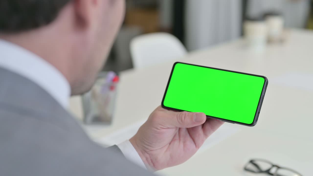 녹색 크로마 키 스크린 을 가진 스마트폰 을 보고 있는 사업가