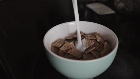 Kanada---Gießt-Frische-Milch-Auf-Quadratisch-Geformte-Müsli-In-Einer-Weißen-Schüssel---Nahaufnahmeaufnahme