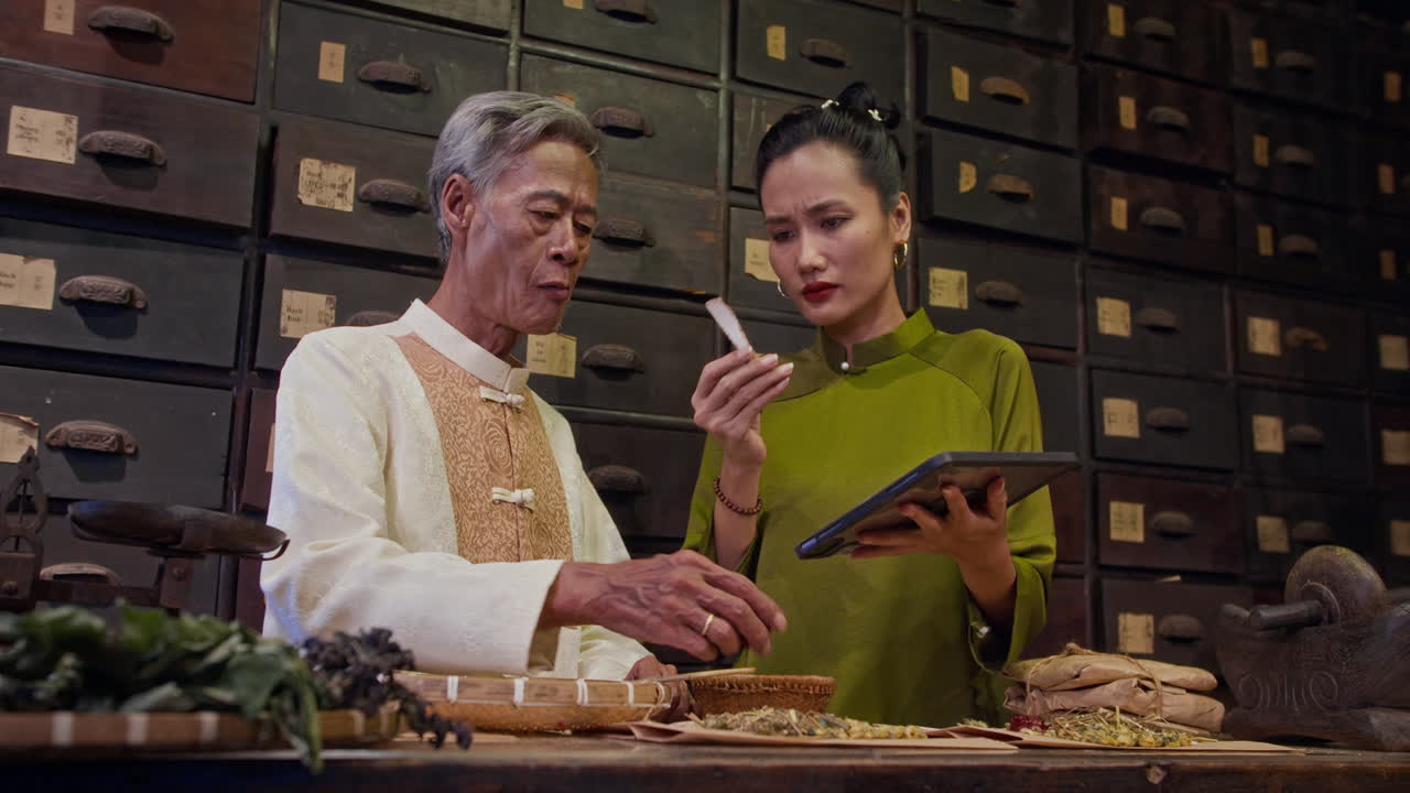 Asian Daughter Listening to Aged Father Talking about Chinese Herbal Medicine