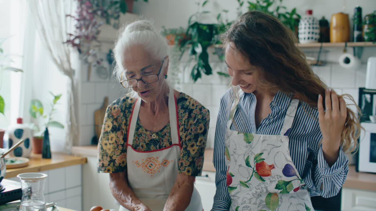 Nonna che legge un libro di ricette con la nipote in cucina