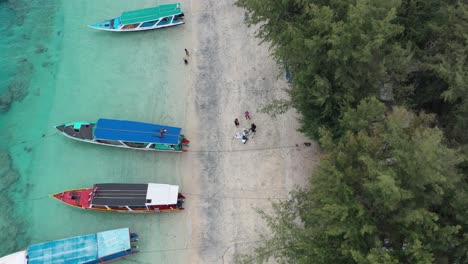 antena de arriba hacia abajo de barcos anclados en una playa de arena blanca en hermosas aguas turquesas en las islas gili trawangan de indonesia