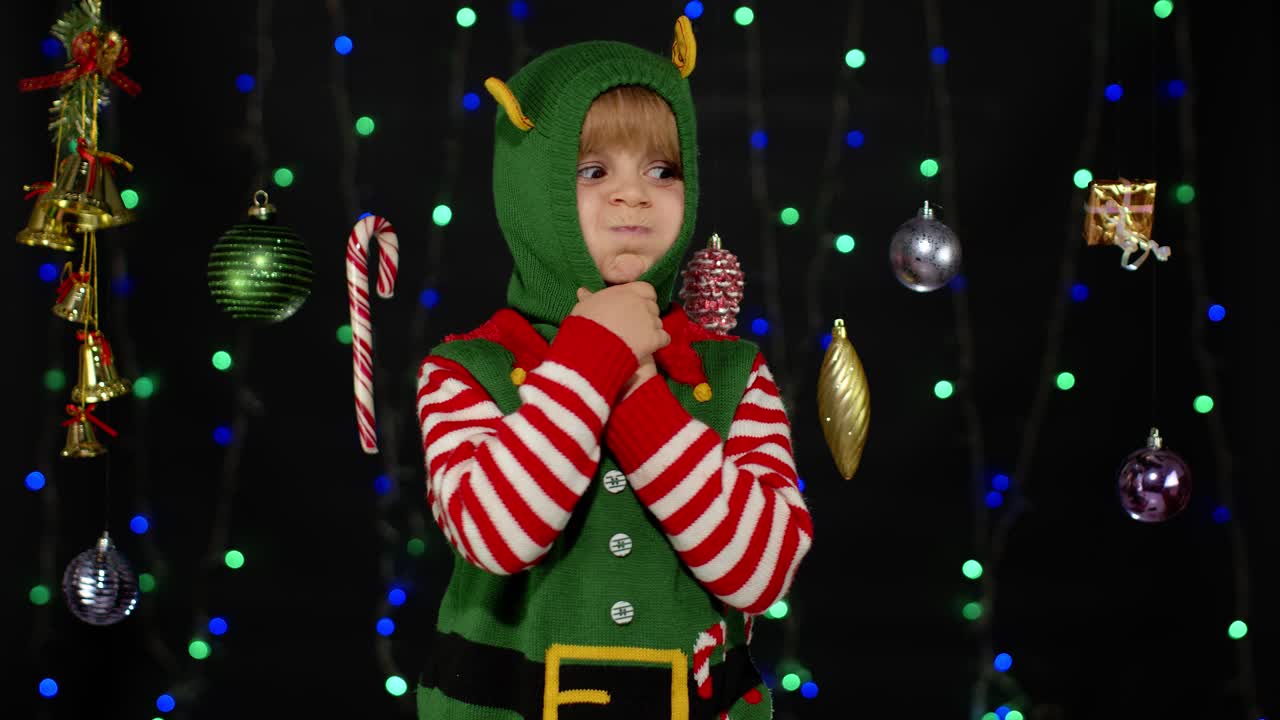 Kid girl in Christmas elf Santa helper costume dancing, fooling around. New Year holiday celebration