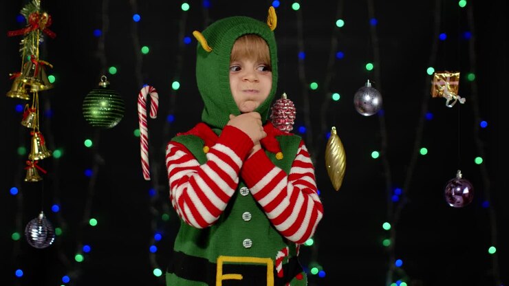 Kid girl in Christmas elf Santa helper costume dancing, fooling around. New Year holiday celebration