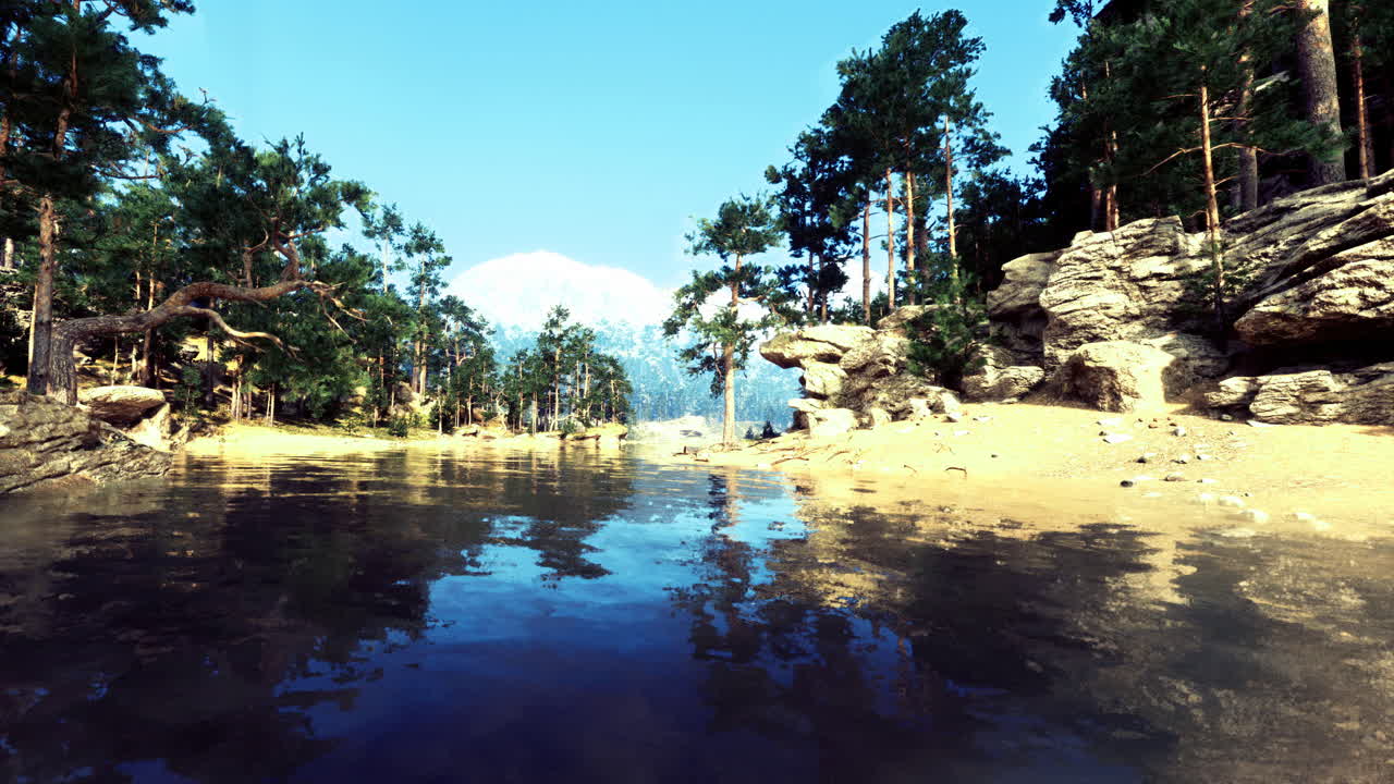 Serene riverbank landscape surrounded by trees and mountains under clear sky
