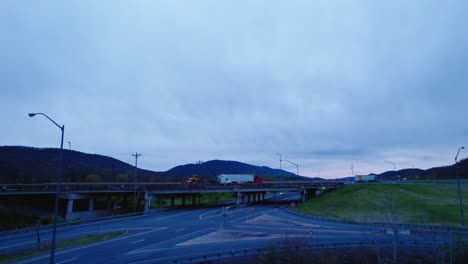 establisher aerial of multiple dry vans and reefers semi trucks on overpass in milesburg, pennsylvania, usa