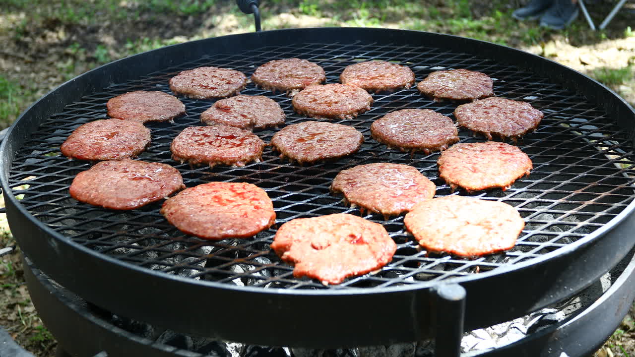 Large grill with many burgers being cooked on an outside