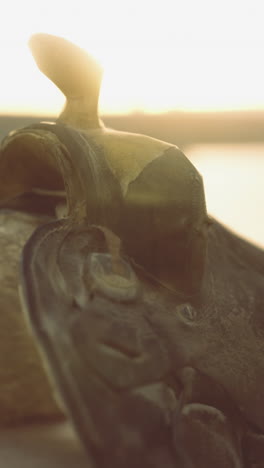 elegant cowboy saddle glimmers under the warm glow of sunset by the riverbank